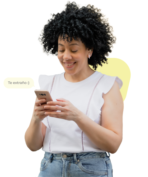 Una mujer con cabello rizado mirando su celular con un mensaje emergente que dice "Te extraño".